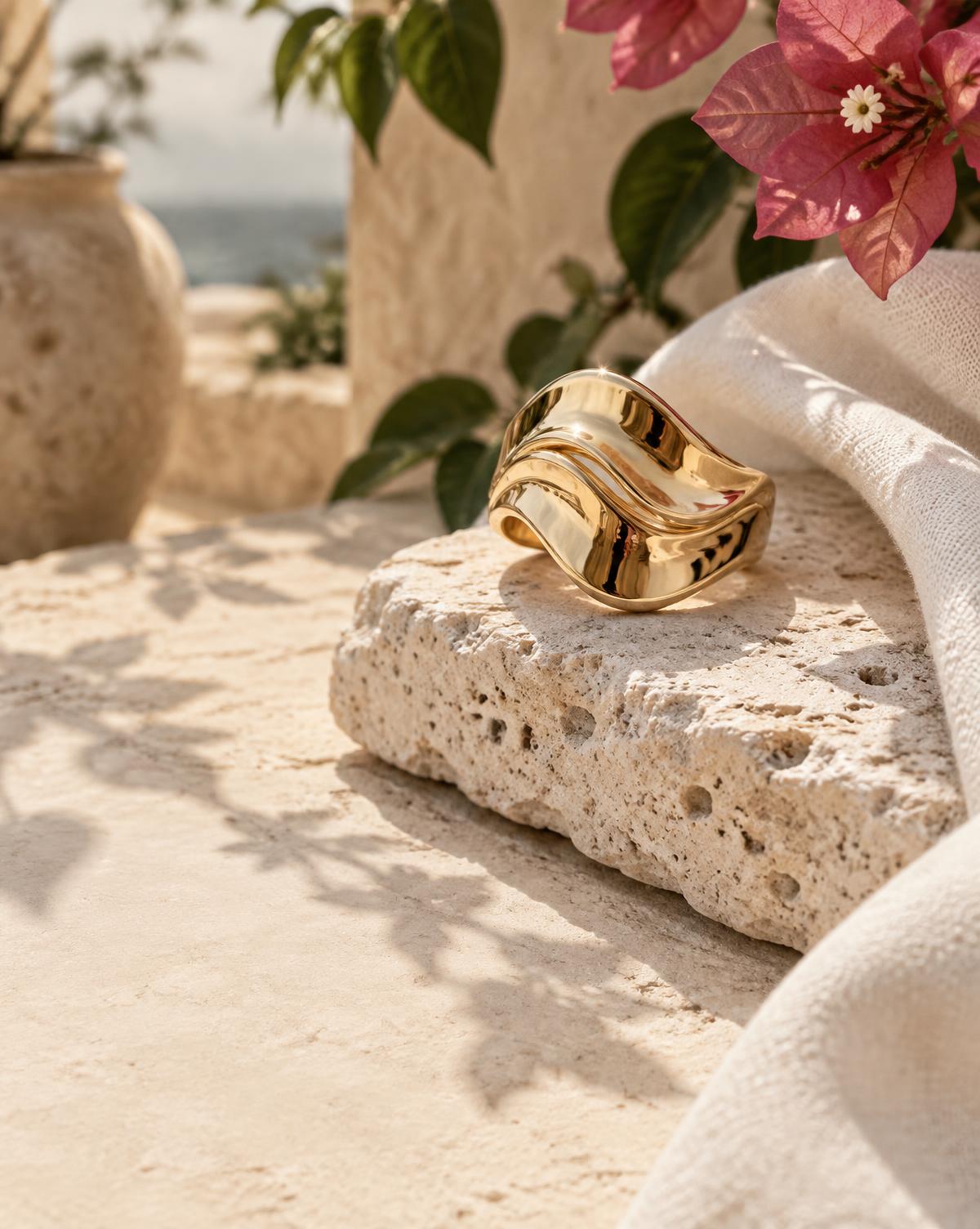 Anillo escultórico dorado sobre piedra caliza y bugambilia